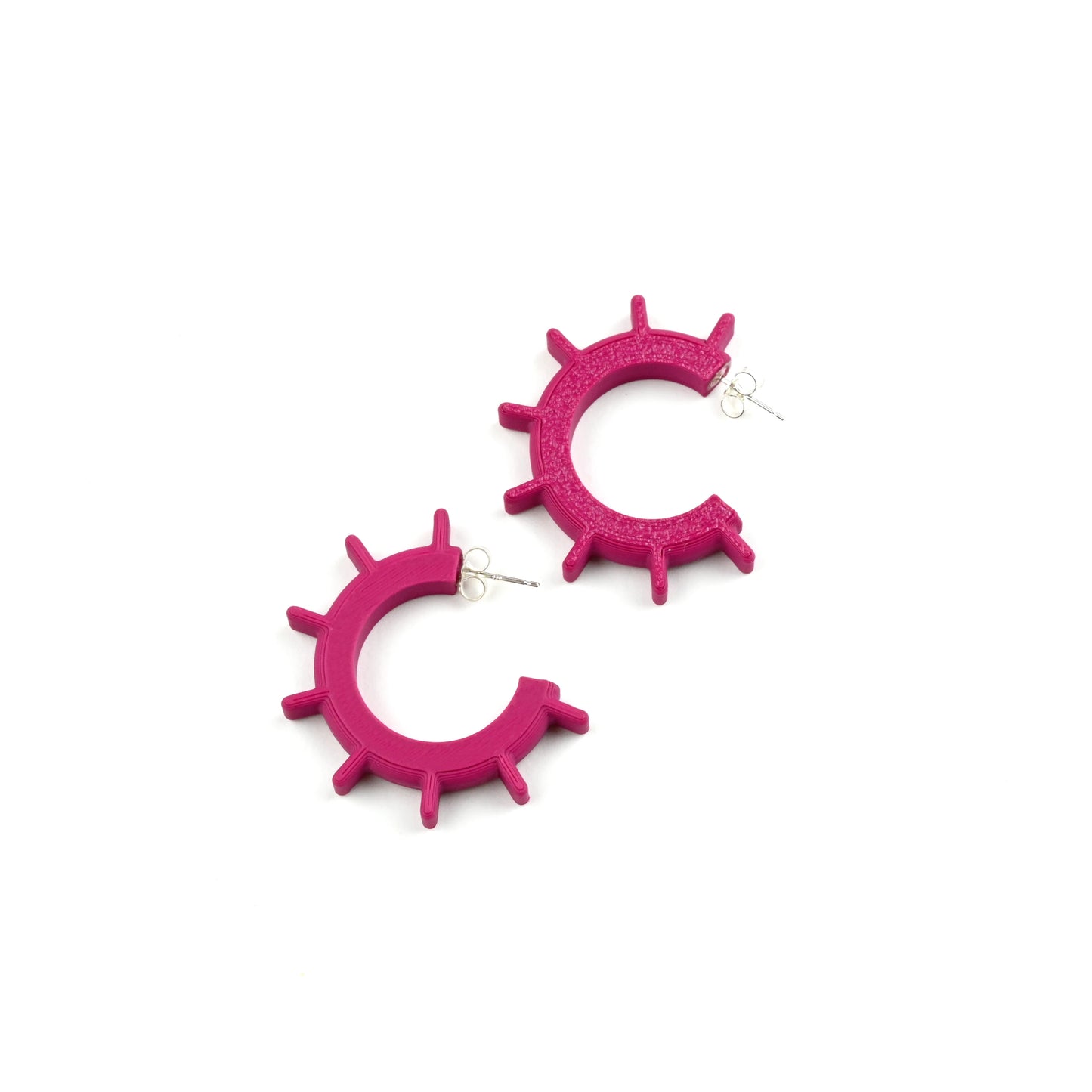 Pair of plum pink hoop earrings with ridge design on a white background