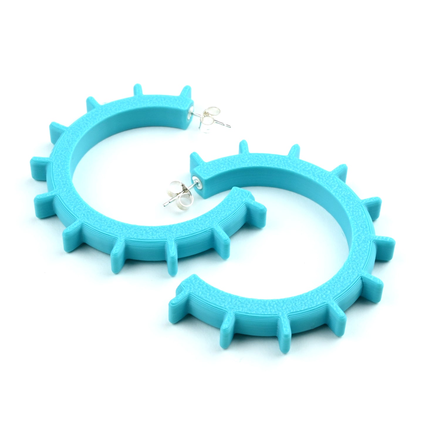 Turquoise plastic hoop earrings with ridge detail along outside of the hoop.  They have silver ear posts and earring scroll backs.