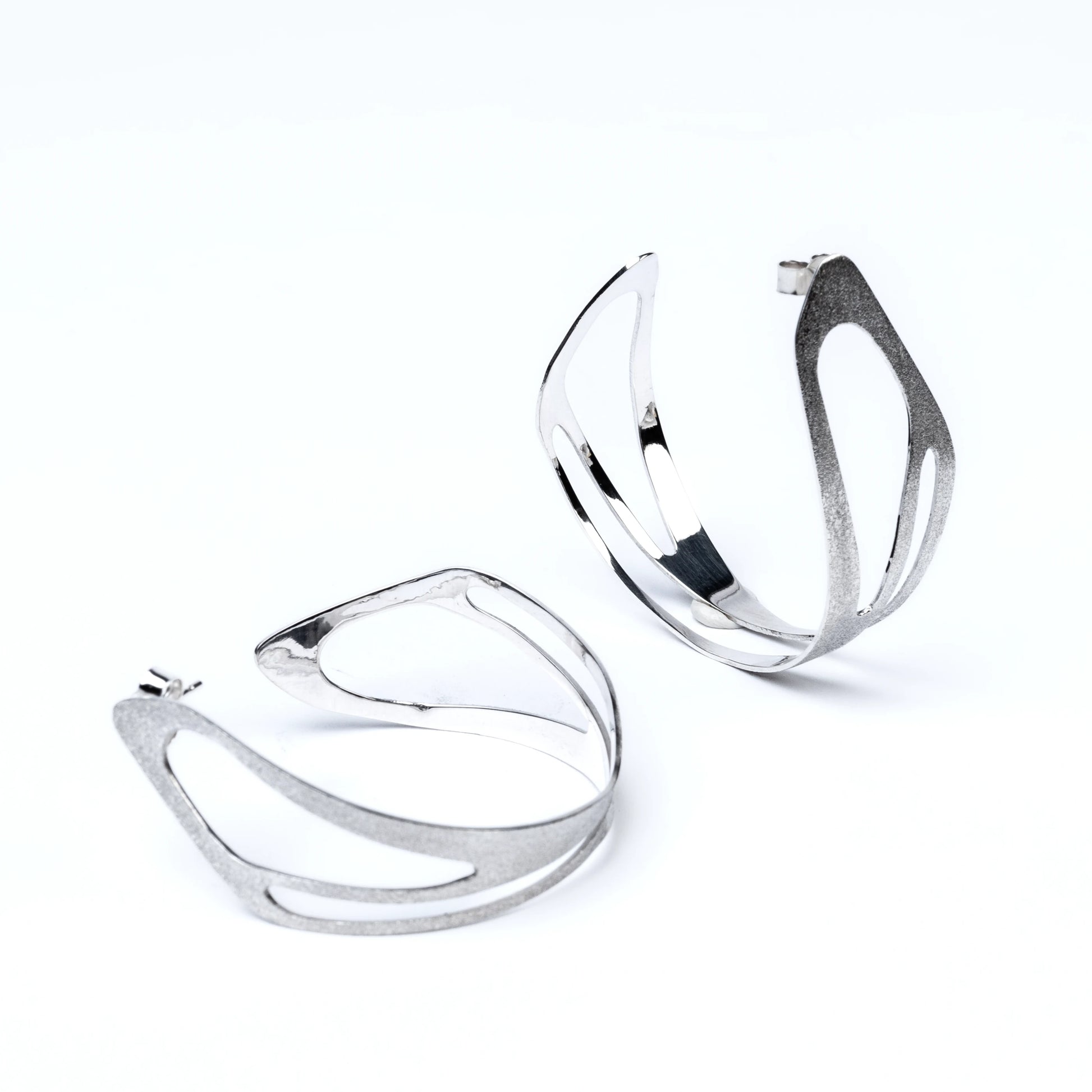 Pair of silver hoop earrings with cut out details on a white background