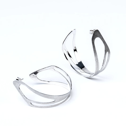 Pair of silver hoop earrings with cut out details on a white background