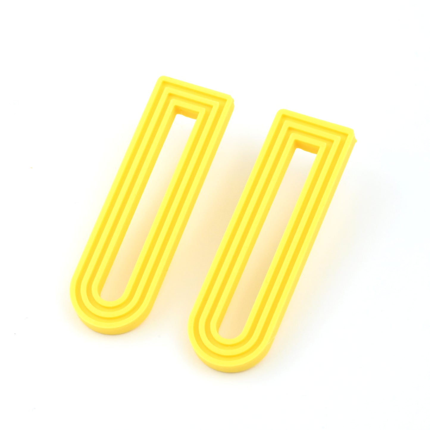 Yellow U-shaped drop earrings with raised linear design on a white background