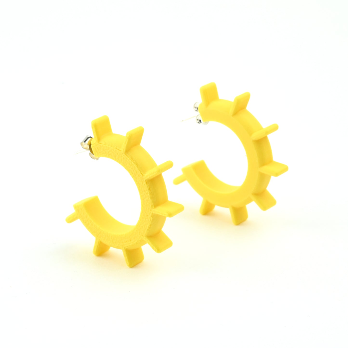Yellow hoop earrings with ridged design and silver ear posts on a white background