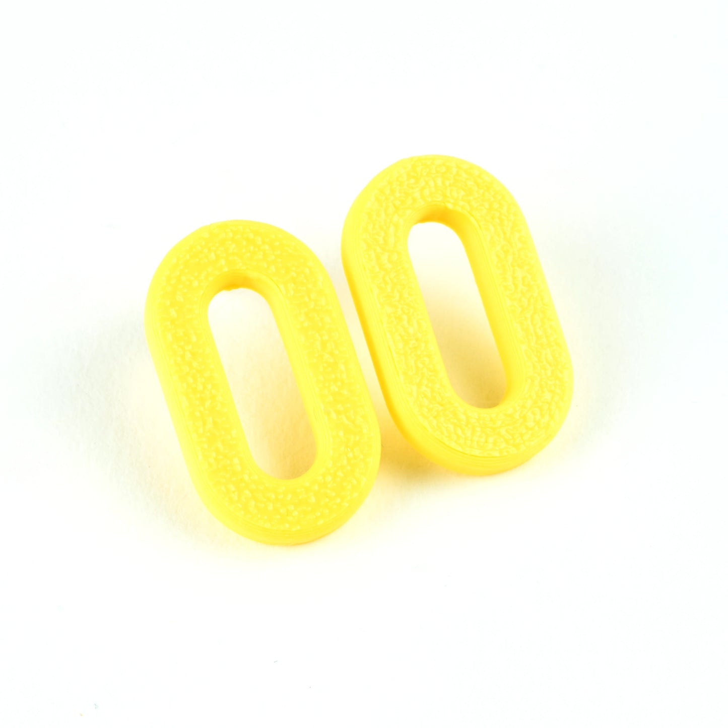 Two oval yellow stud earrings with a textured surface on a white background